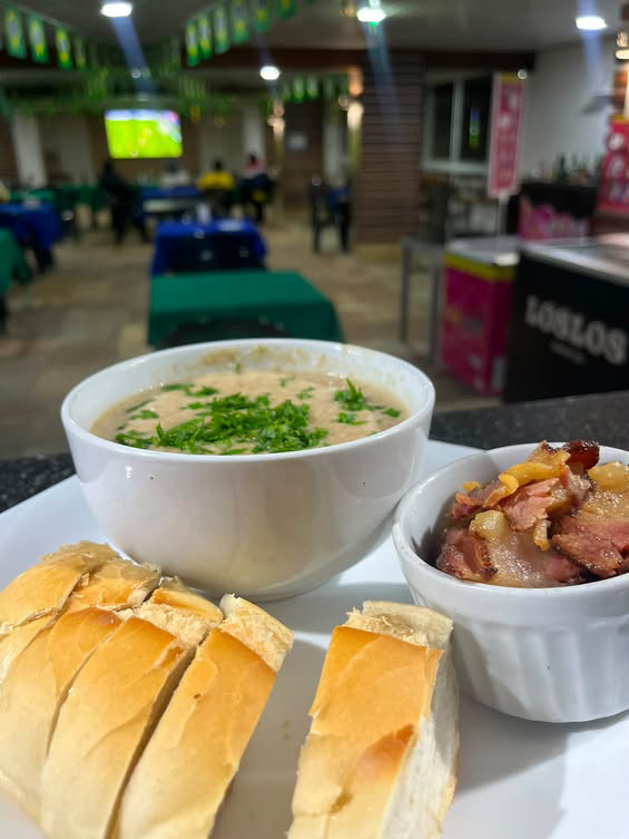 Tigela de caldo com ervas, pão e acompanhamento no BIMA